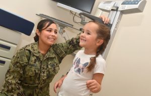 A military doctor measuring a child.