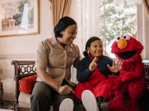 A parent and child playing with Elmo.