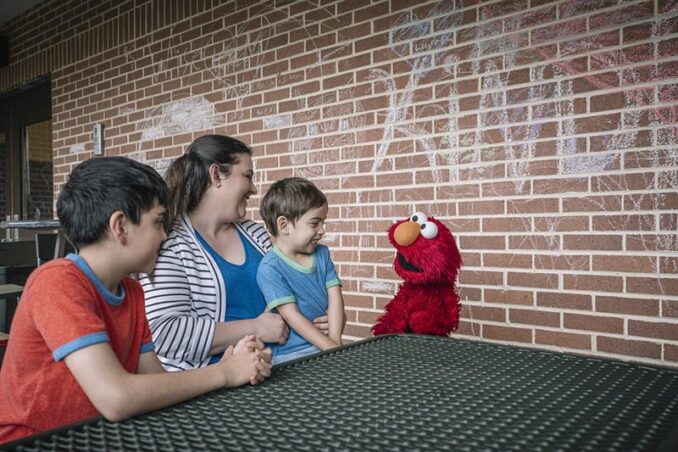 Elmo talking to a family.